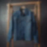 A vintage long denim jacket hanging on a wooden rack